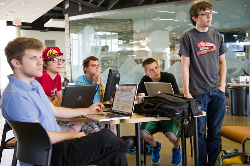 A class watching a presentation in a glass room